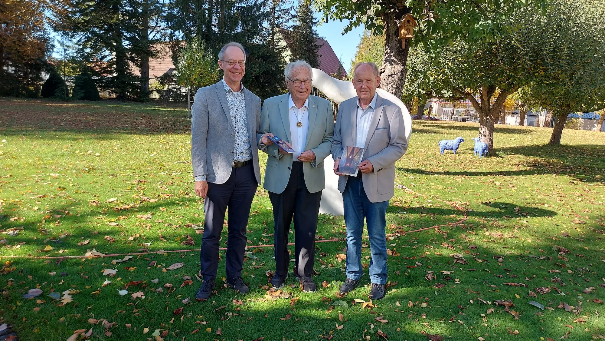Das Foto zeigt Prof. Dr. Manfred Riegger (links), der an der Universität Augsburg die Erarbeitung der Broschüre initiiert und geleitet hat, zusammen mit Verleger Josef Fink (rechts) bei der Übergabe der Publikation an Siegfried Denzel, dem Stifter der Kapellen. Foto: Alfred Mundi, Siegfried und Elfriede Denzel Stiftung